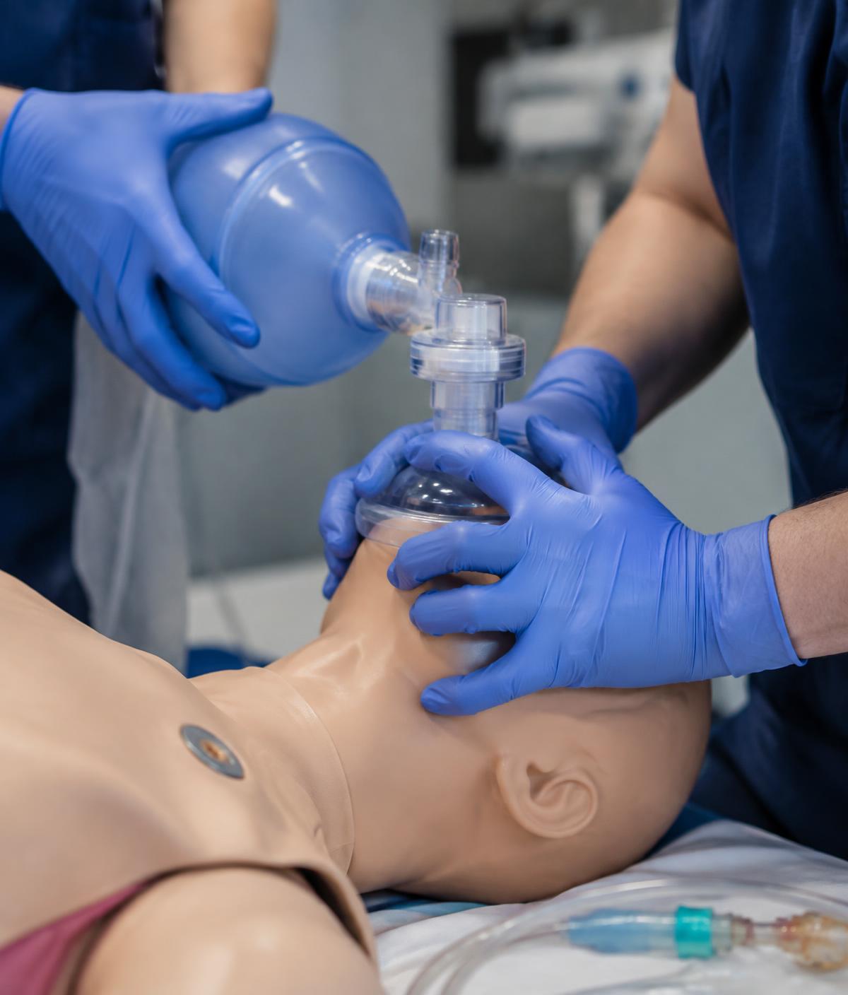 Mãos realizando ventilação com bolsa-válvula-máscara em manequim